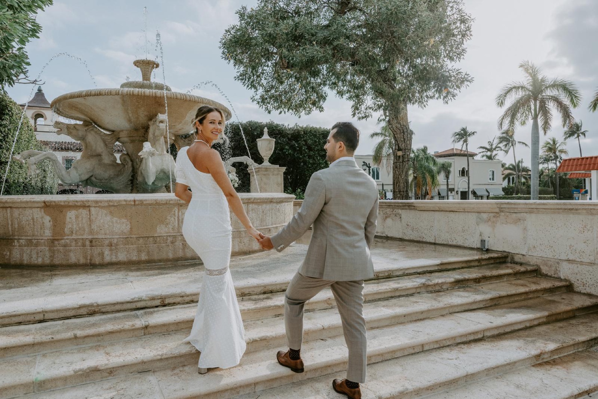 Bride and groom holding hands beside the Worth Avenue fountain in Palm Beach, Florida
