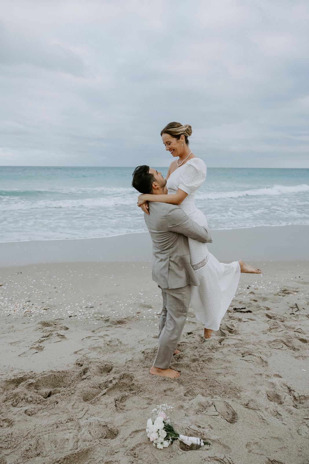 Groom lifting the bride at the shoreline during a South Florida beach wedding
